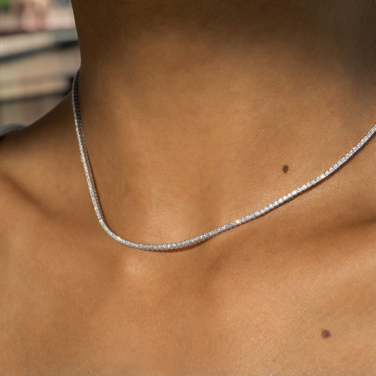 a close up photo of a woman's neck wearing a classic four prong diamond necklace