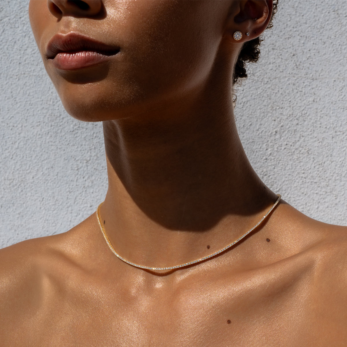 a woman wearing a 14K yellow gold bezel setting diamond stud and a tennis necklace