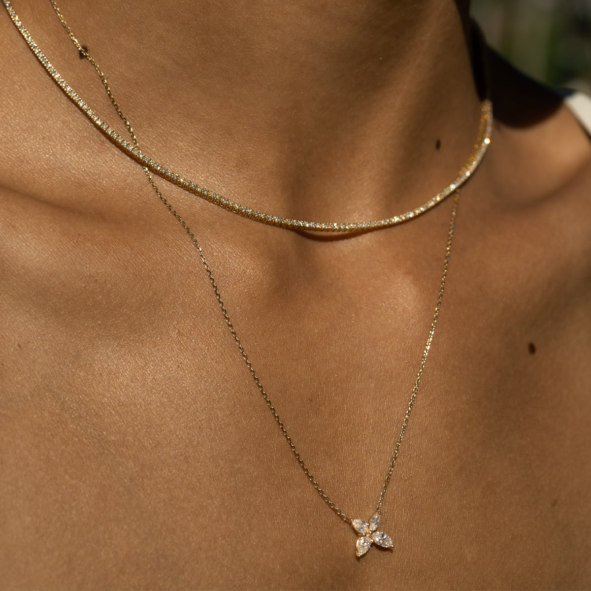 a close up photo of a woman wearing a tennis bracelet and floral design marquise cut diamond necklace
