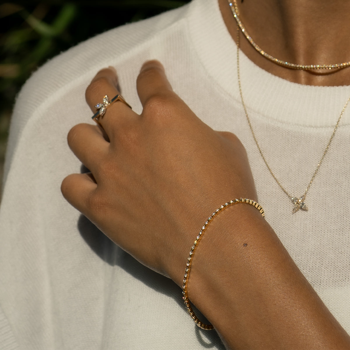 a woman wearing a thin tennis bracelet, matching with a marquise diamond ring and necklaces