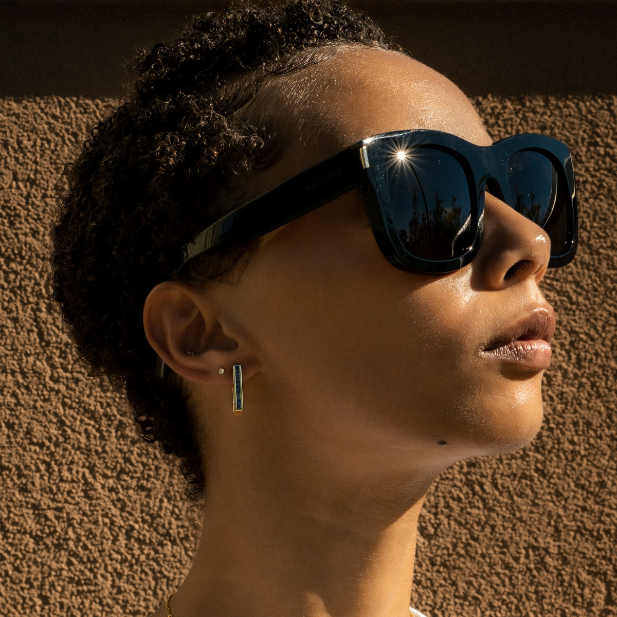 a woman earing blue sapphire gold earrings