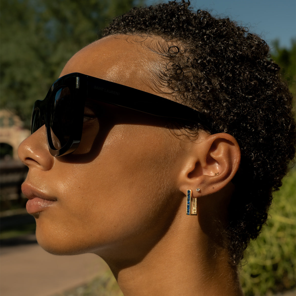 a woman earing blue sapphire gold earrings