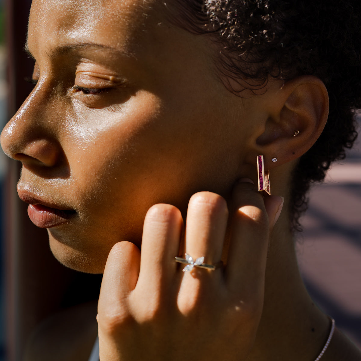 a woman wearing 14K yellow gold princess cut ruby rectangular hoop earrings
