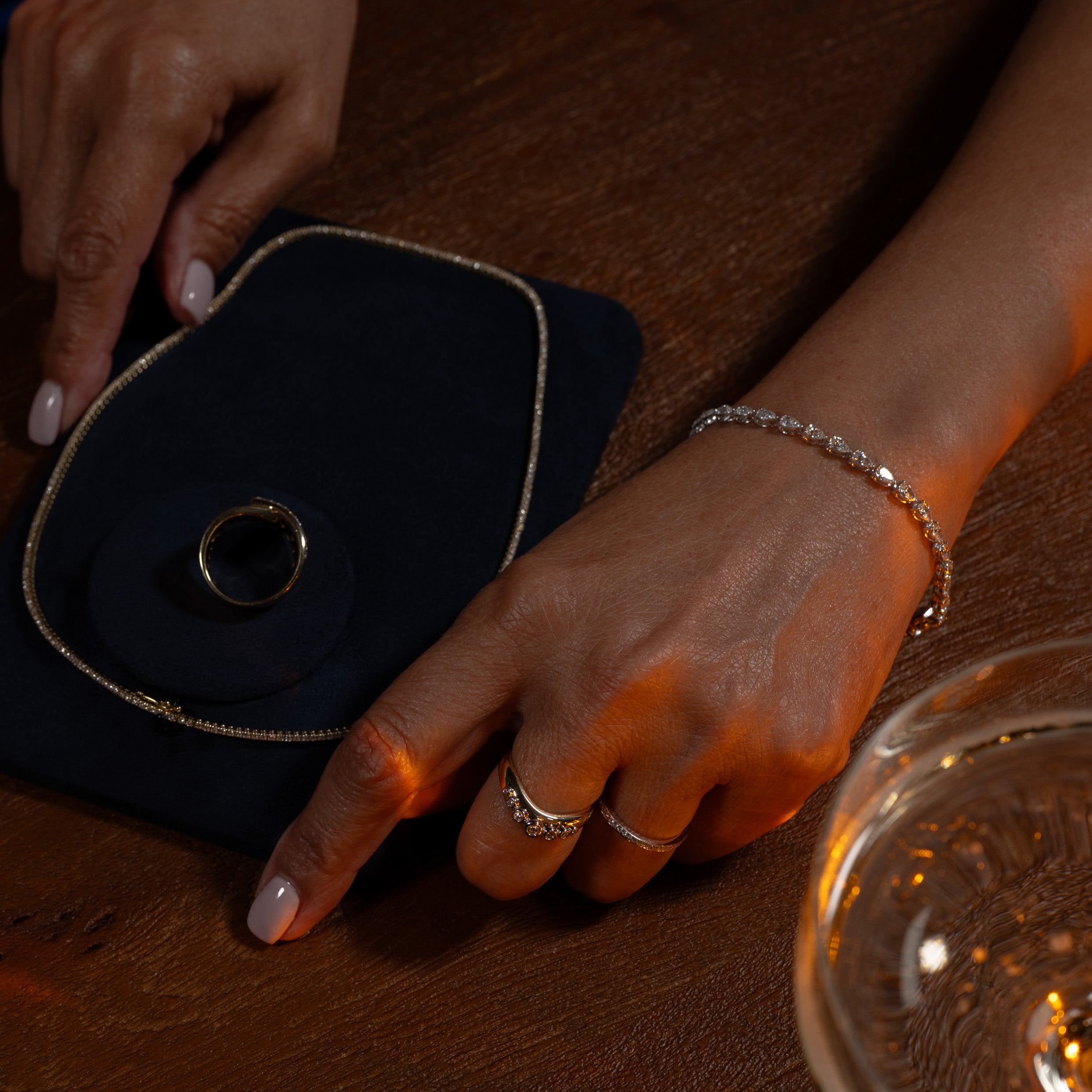 Hand with diamond bracelet and rings on a wooden coffee table