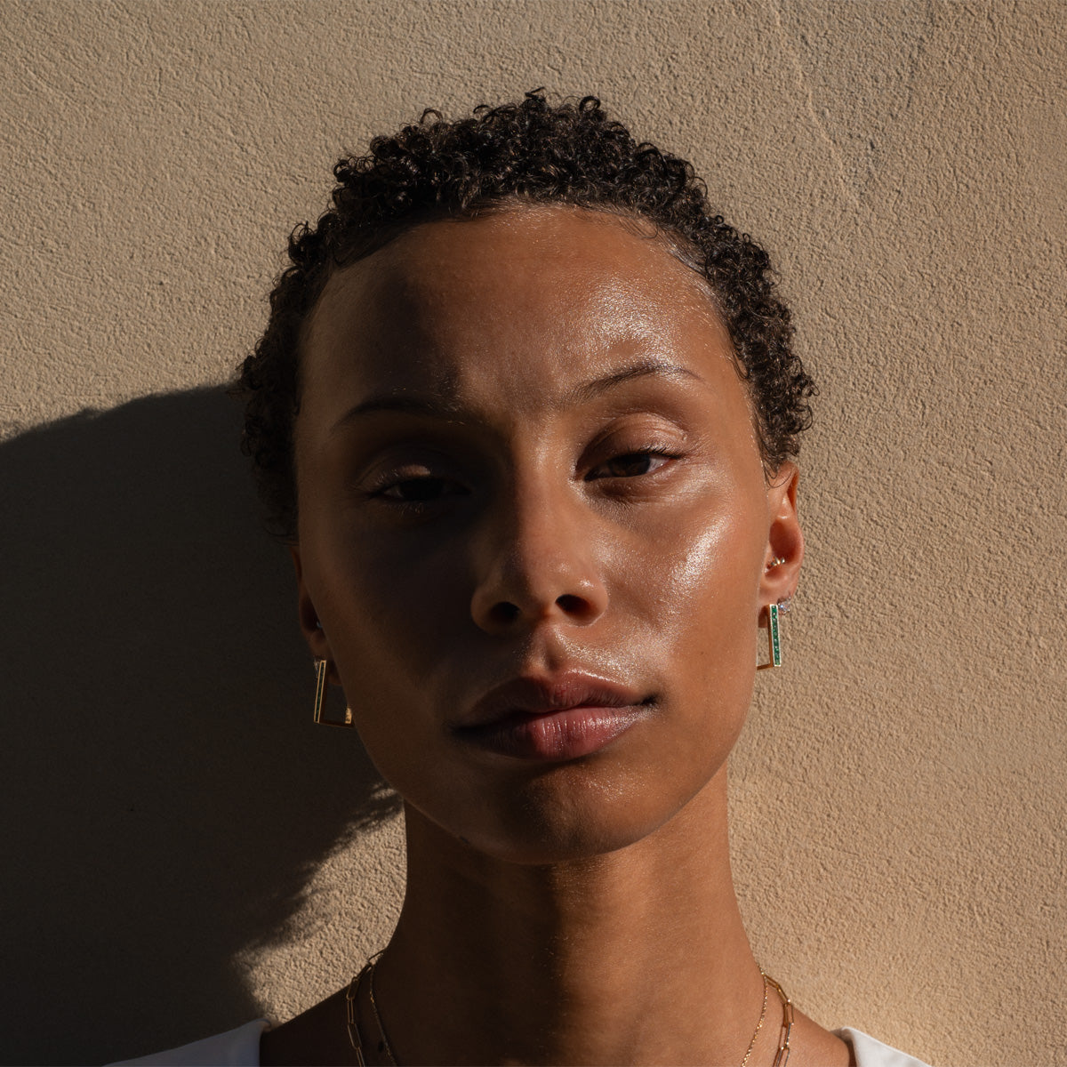 a model wearing emerald gold earrings