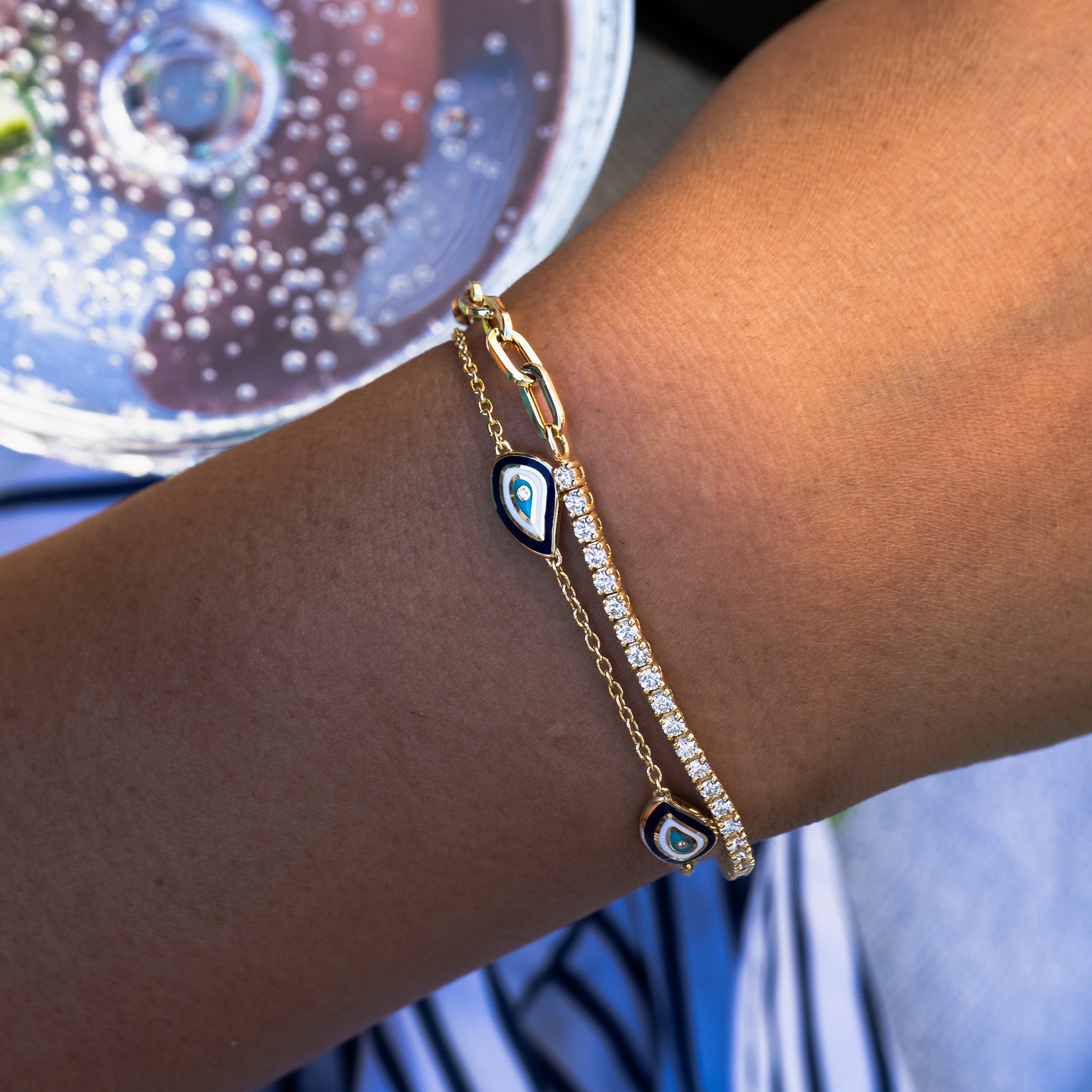 Solid gold diamond bracelet with an evil eye design worn on a wrist, blurred background