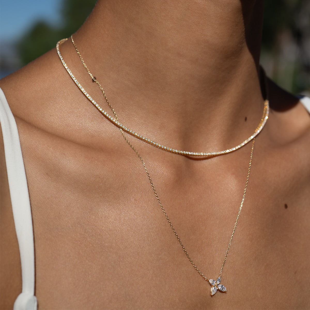 a woman wearing a tennis necklace layering with a marquise cut diamond necklace