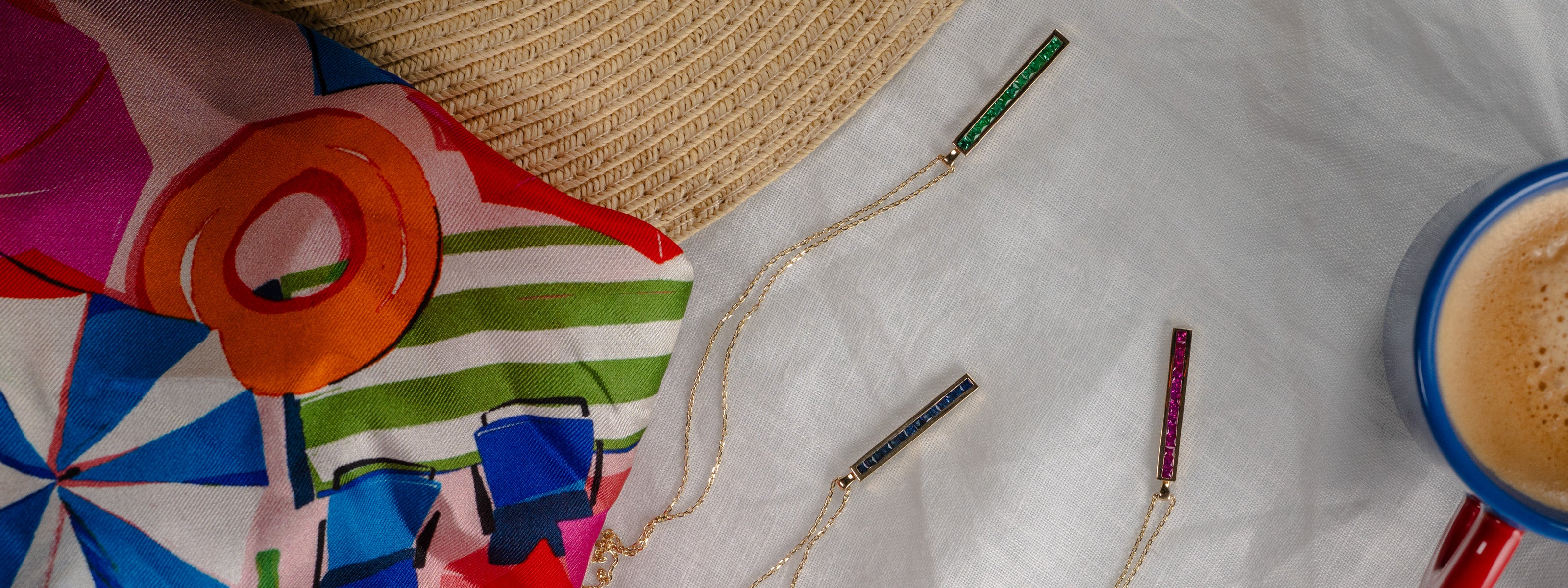 Solid gold linear gemstone pendant necklaces styled with a luxury silk scarf and coffee