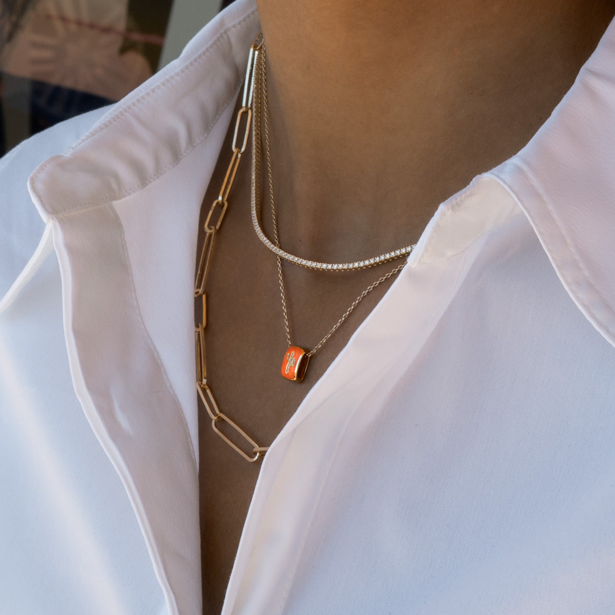 a woman wearing an orange enamel cactus charm matching with diamond tennis necklace and a gold chain