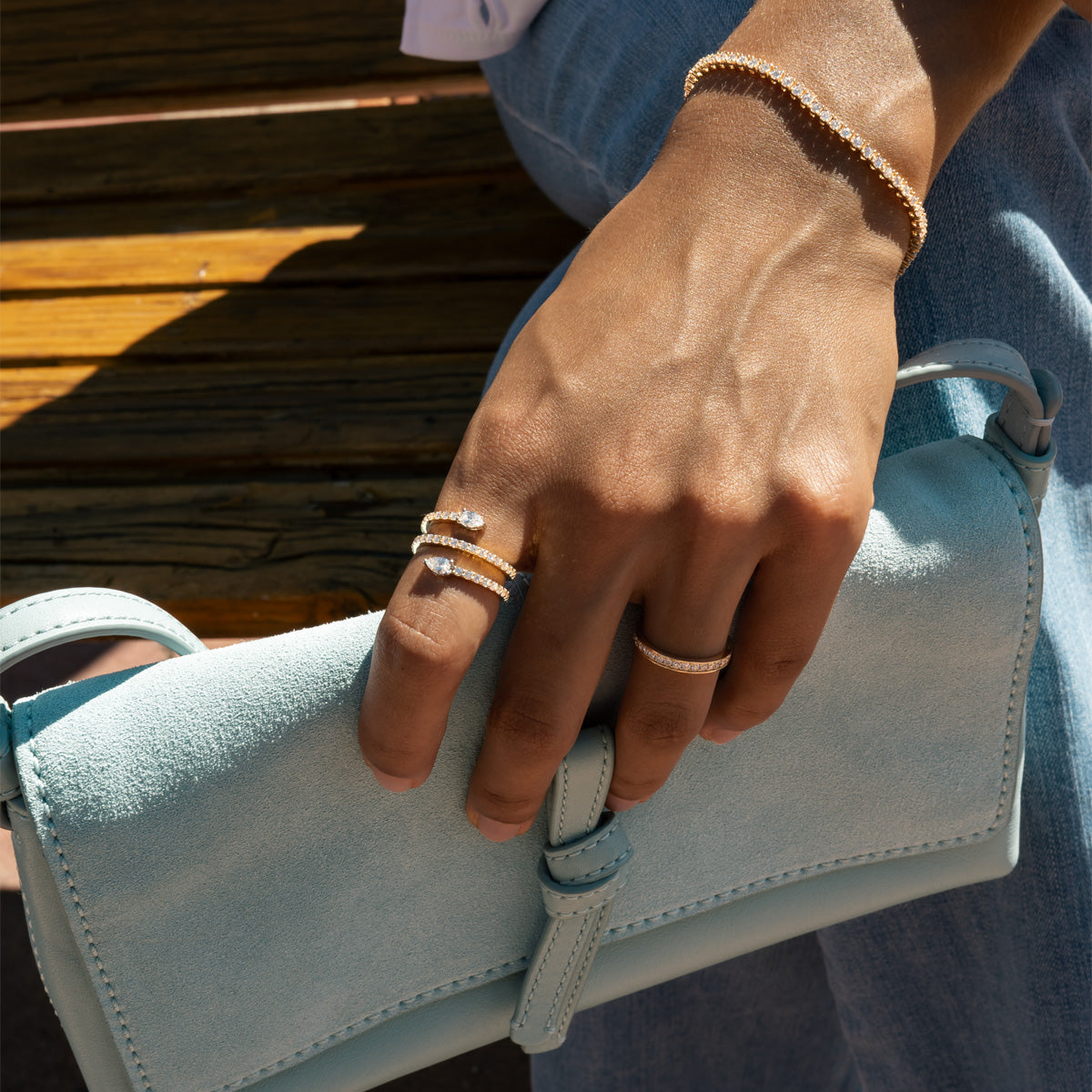 a woman wearing solid gold diamond serpent statement rings on her hand matching with a tennis bracelet and eternity diamond ring