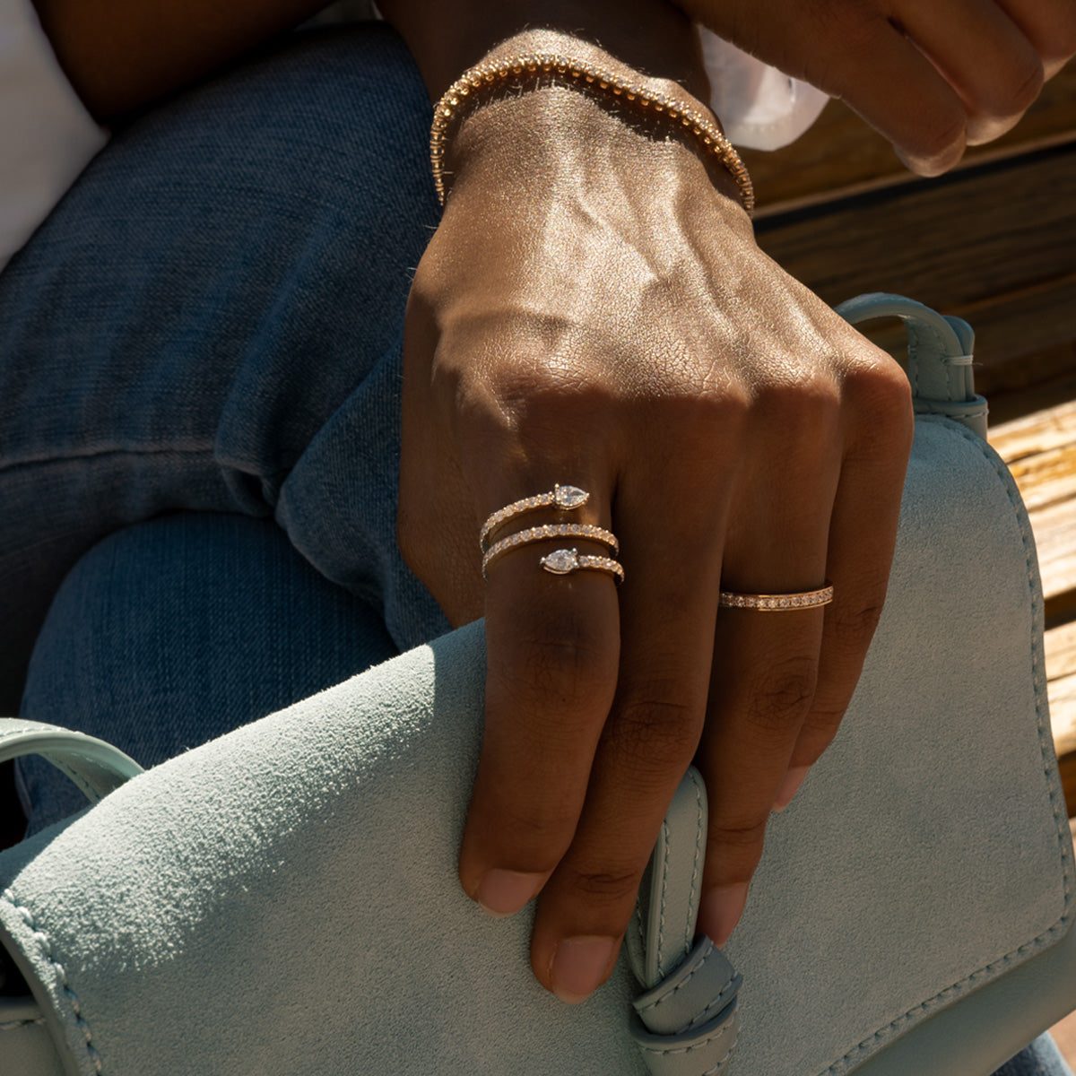 a woman wearing solid gold diamond serpent statement rings on her hand matching with a tennis bracelet and eternity diamond ring