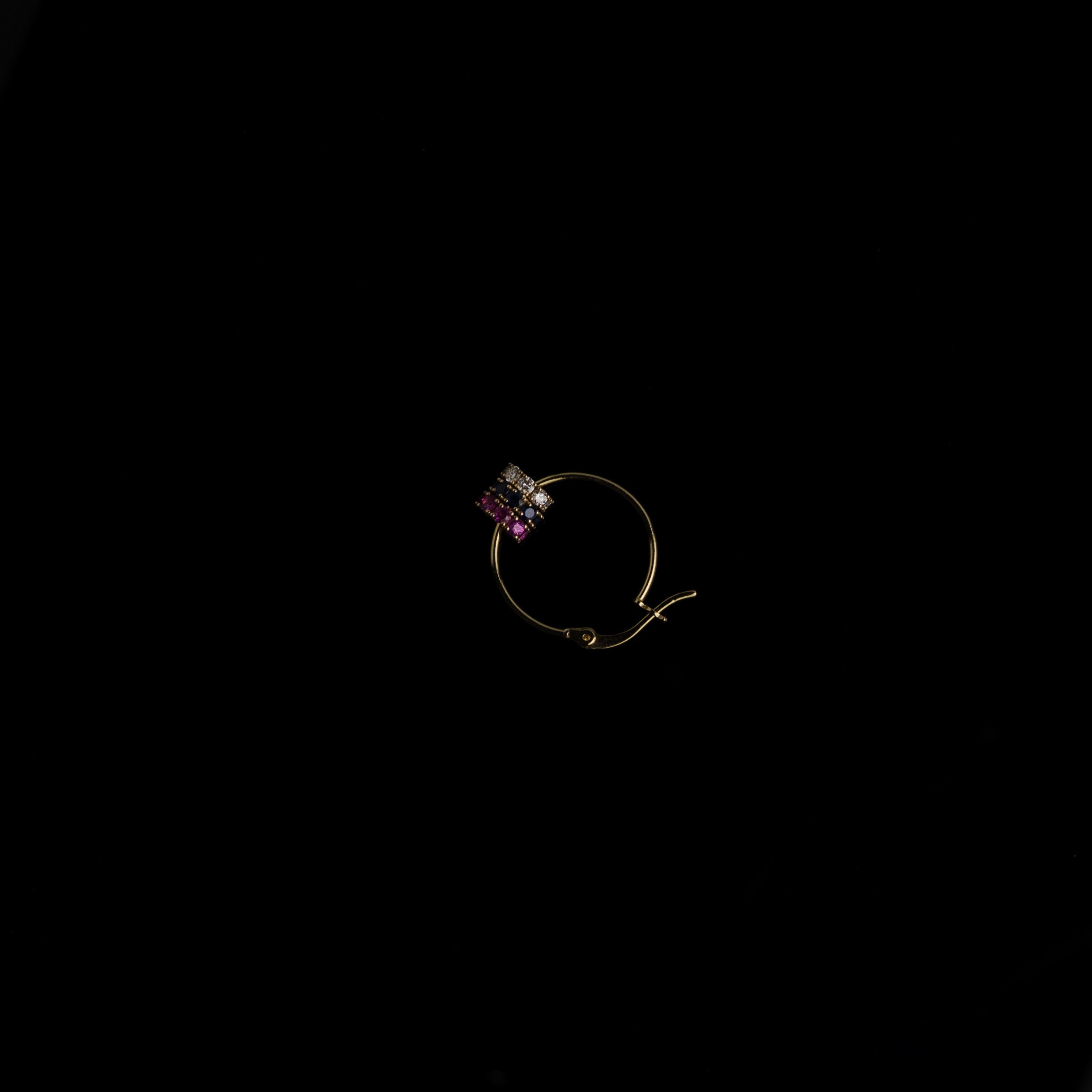Gold earring with sapphires and diamonds on a black background