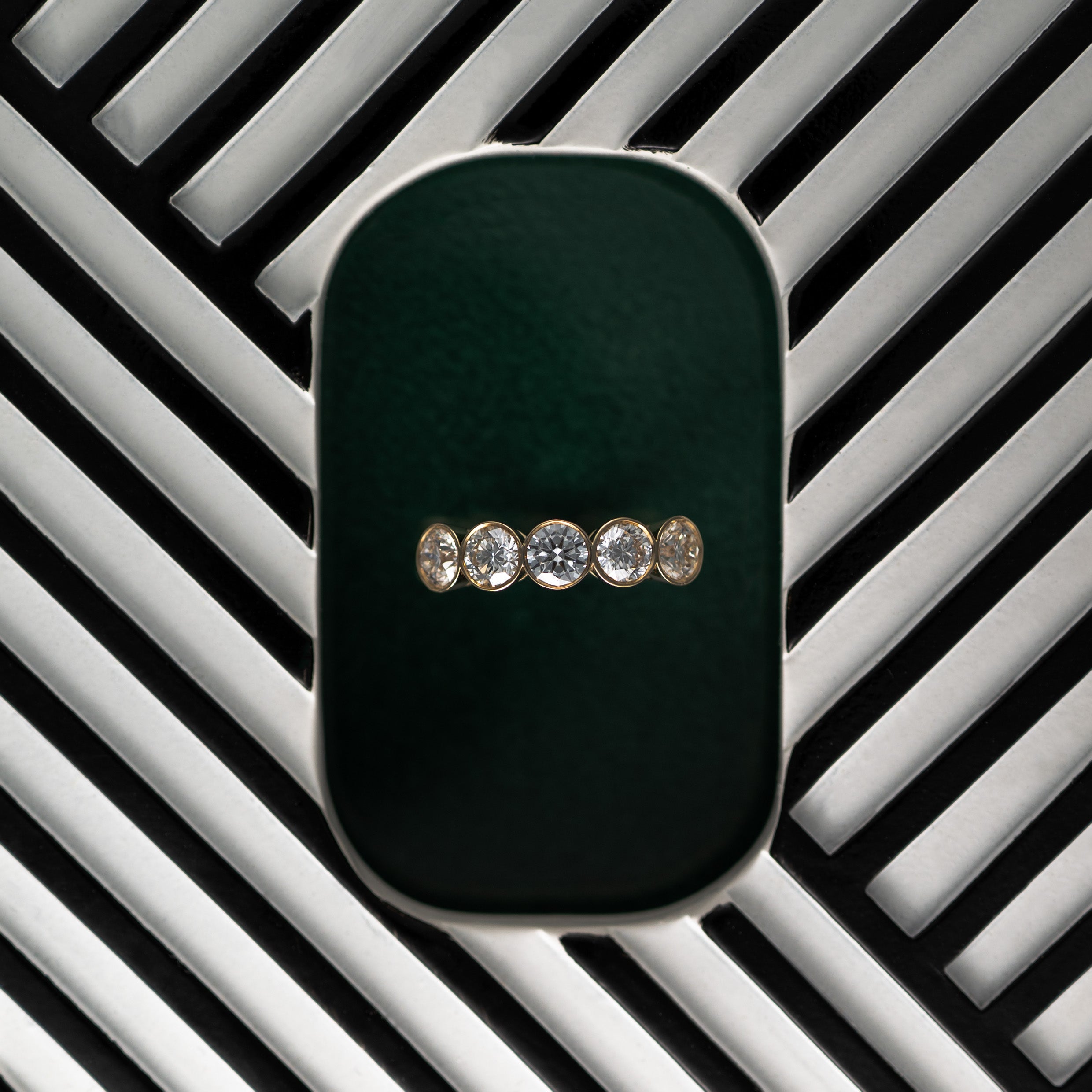 14K gold five stone diamond ring on a black and white striped background