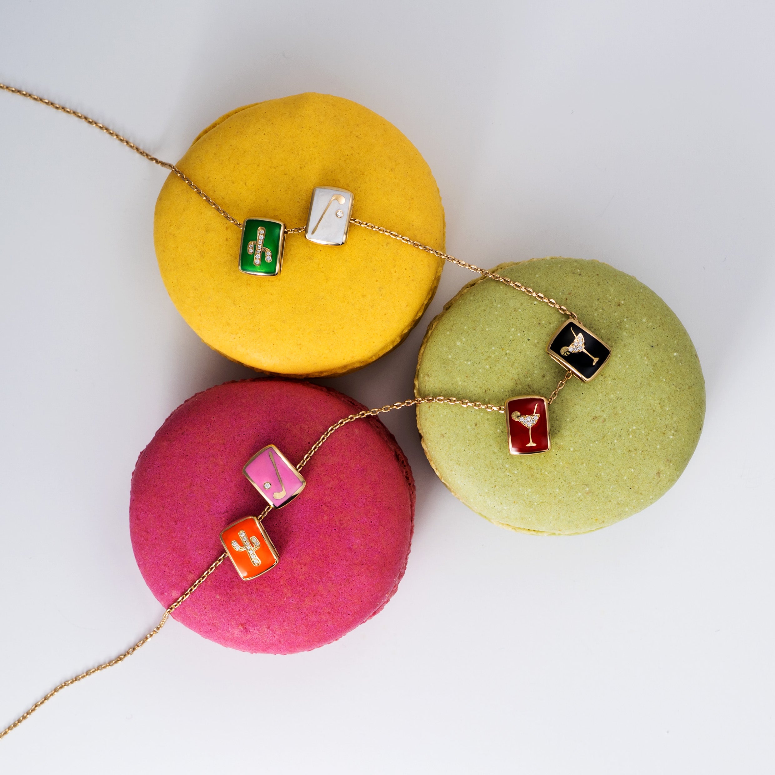 Colorful diamond and enamel charms arranged on top of assorted macarons against a clean white background